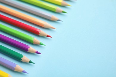 Colorful wooden pencils on light blue background, closeup. Space for text