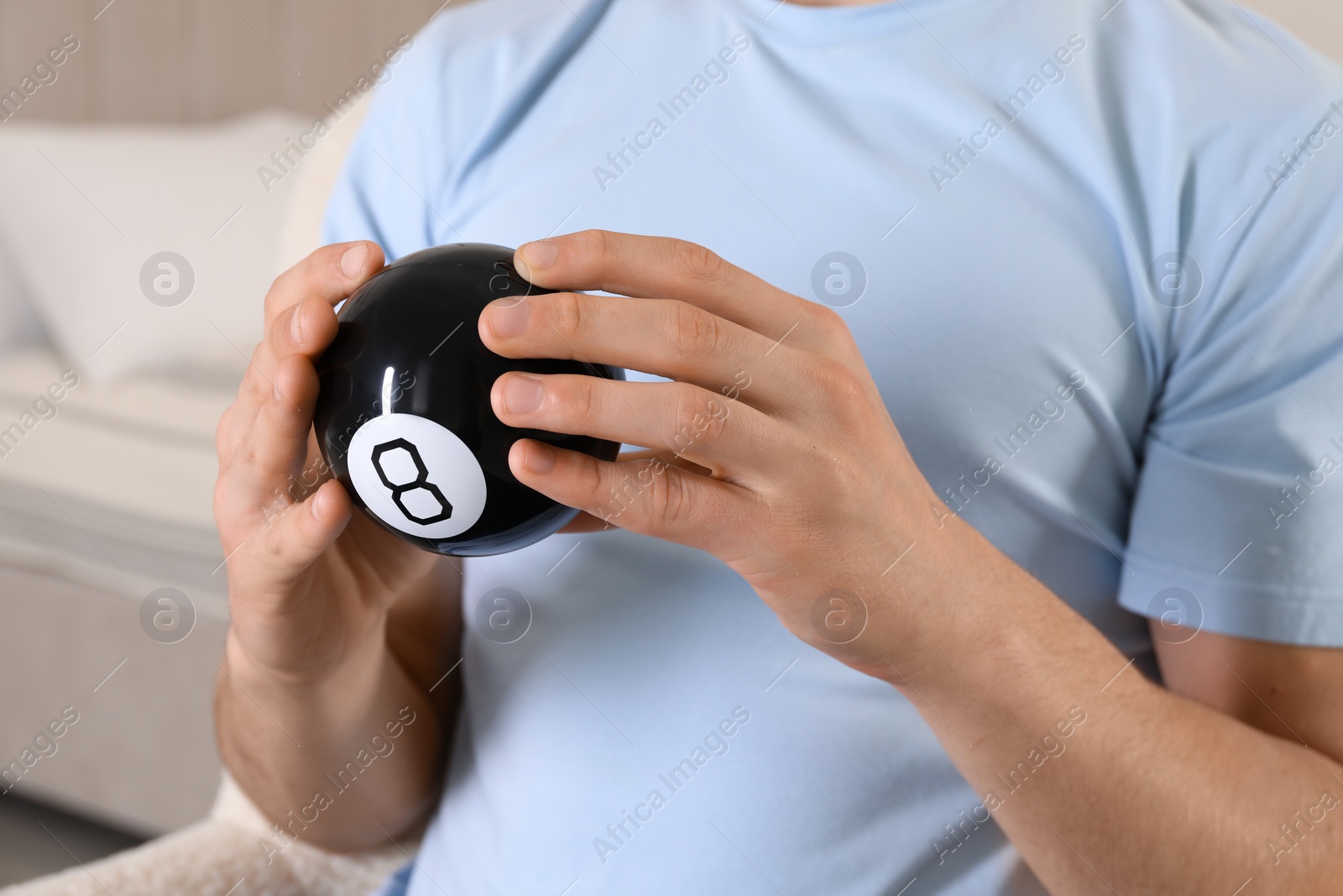 Photo of Man holding magic eight ball indoors, closeup