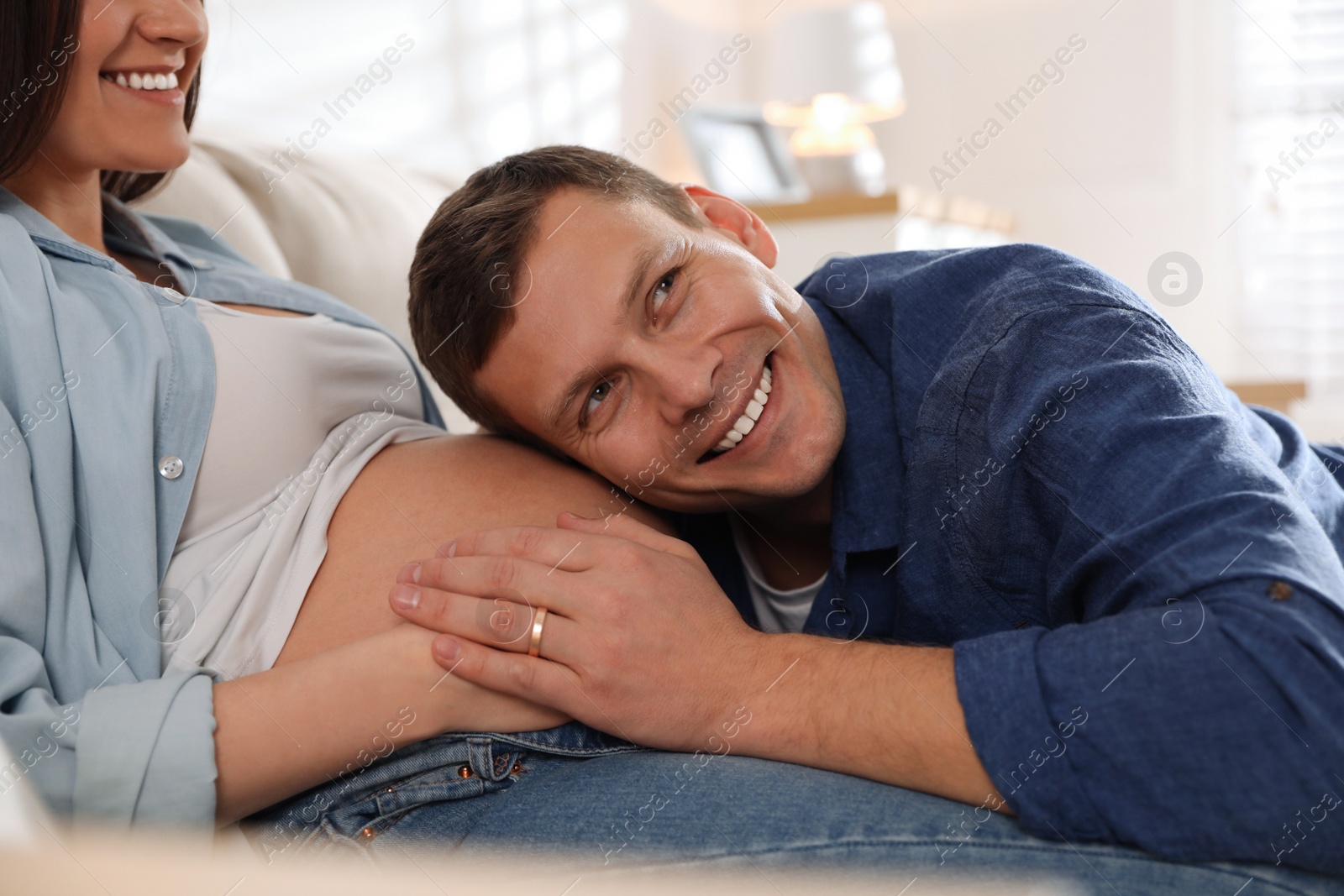 Photo of Young pregnant woman with her husband indoors, closeup