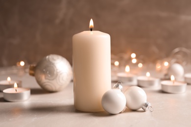Photo of Burning wax candle and Christmas decorations on table