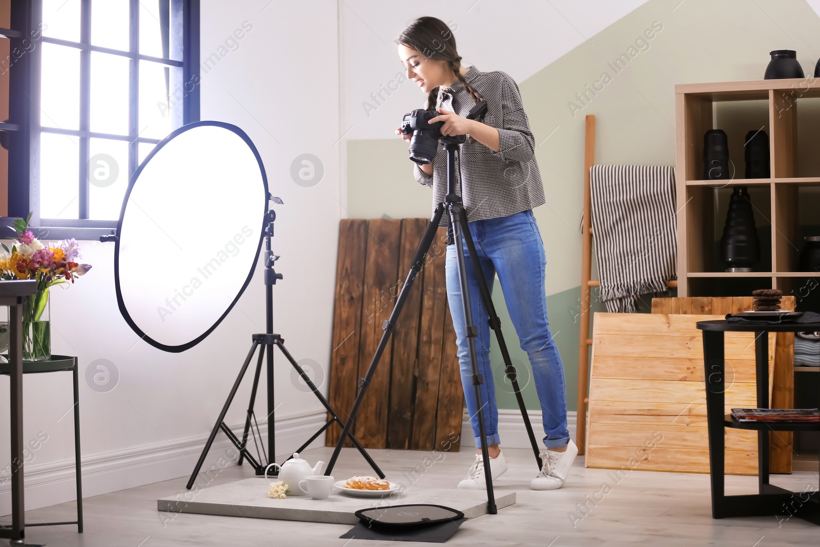 Photo of Young woman with professional camera taking food photo in studio