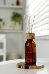 Aromatic reed air freshener on white table in room