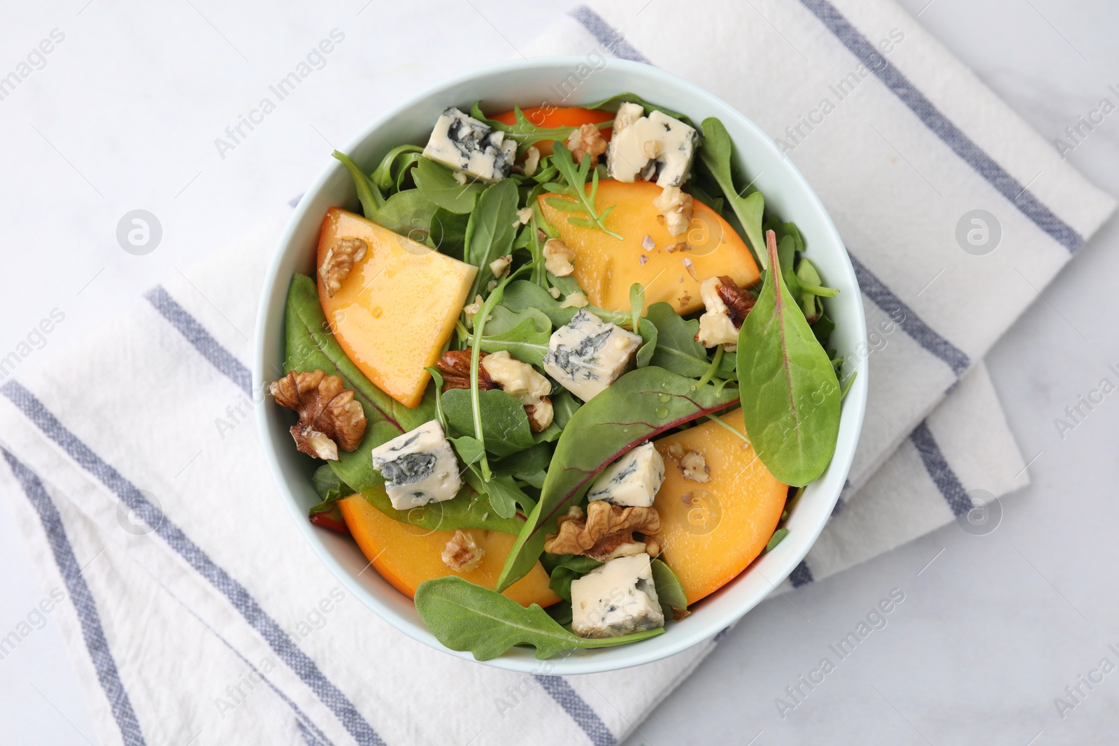 Photo of Tasty salad with persimmon, blue cheese and walnuts served on white marble table, top view