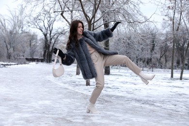 Photo of Young woman falling on slippery icy pavement in park