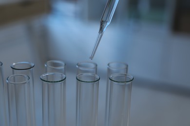 Laboratory analysis. Dripping liquid into test tubes indoors, closeup