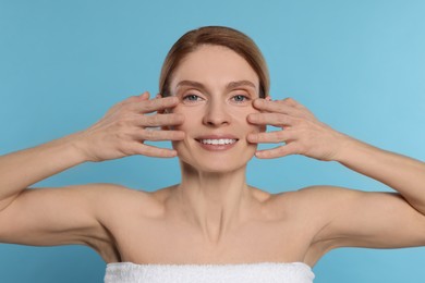 Photo of Woman massaging her face on turquoise background