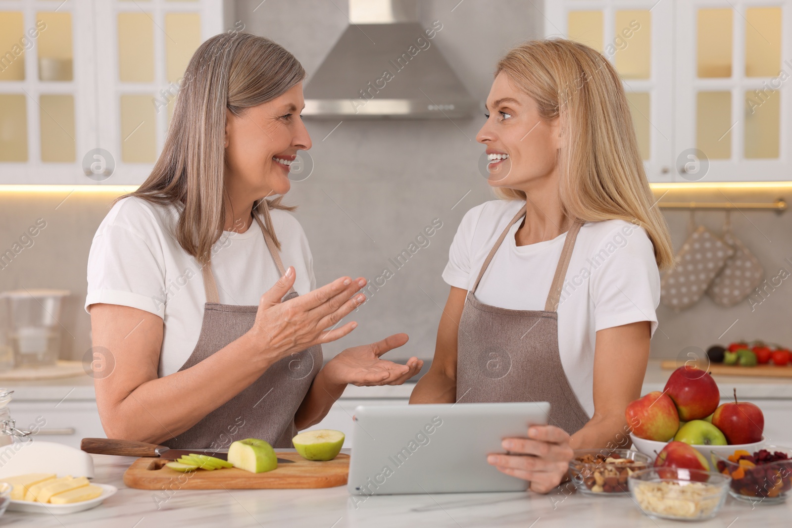Photo of Happy mature mother and her daughter with tablet in kitchen