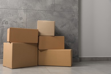 Photo of Many closed cardboard boxes on floor indoors. Delivery service