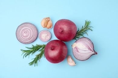 Fresh red onions, garlic and rosemary on light blue background, flat lay