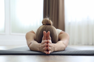 Photo of Young woman practicing restorative asana pose in yoga studio, focus on hands