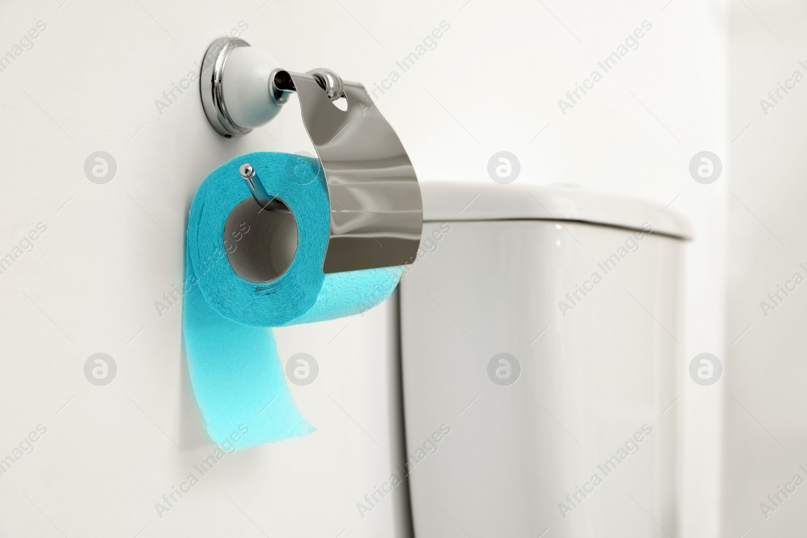 Photo of Holder with toilet paper roll on white wall in bathroom. Space for text