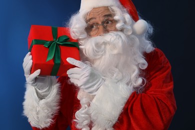 Photo of Santa Claus with Christmas gift on dark blue background