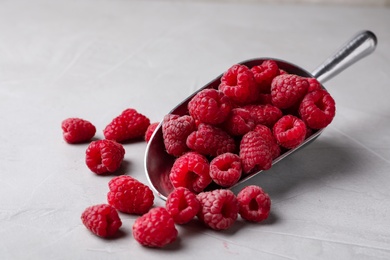 Photo of Scoop with delicious ripe raspberries on light background