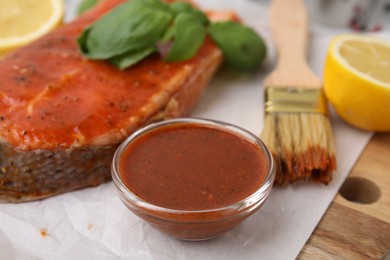 Photo of Fresh marinade, fish, lemon, brush and basil on table, closeup