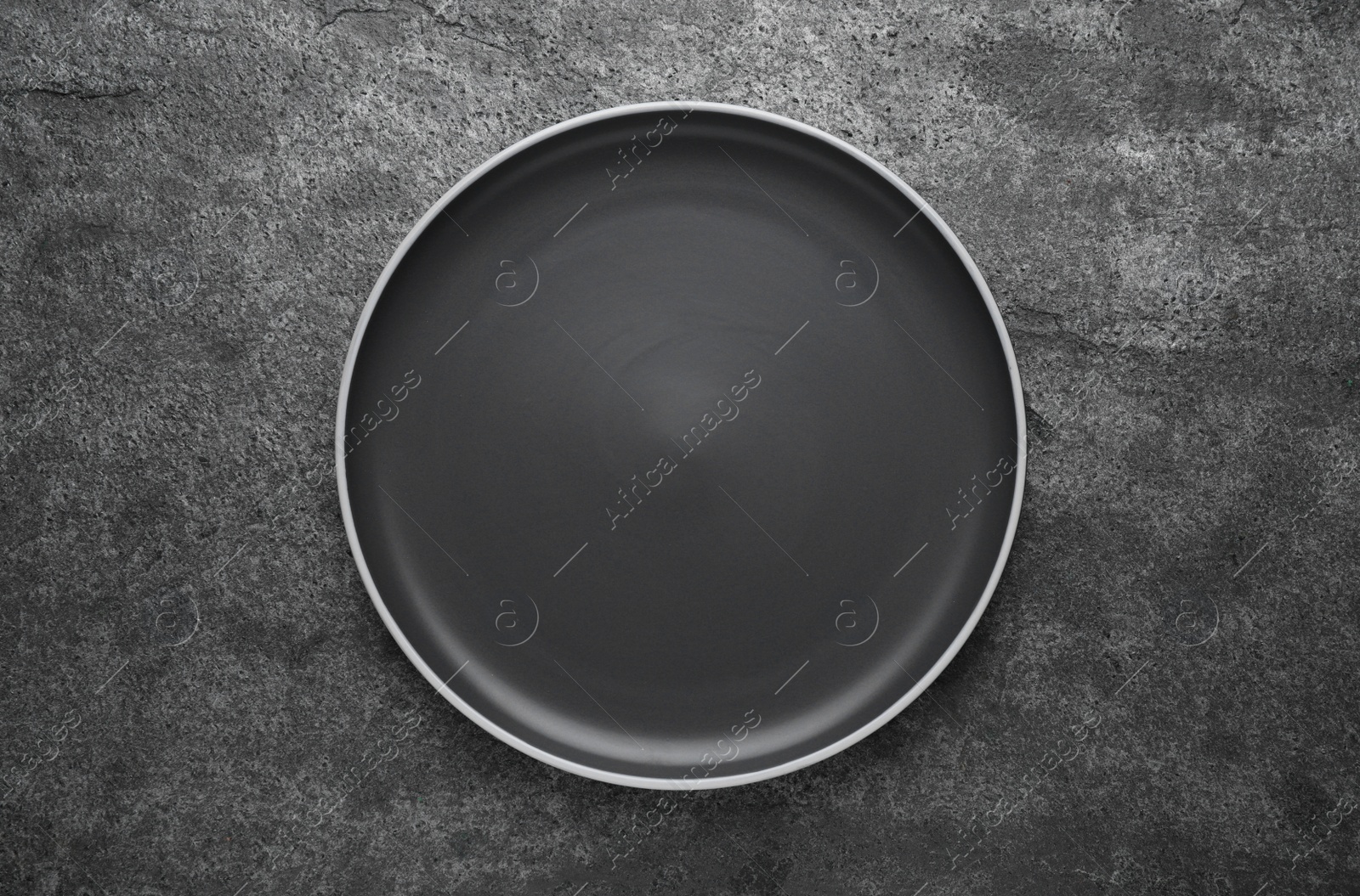 Photo of New dark plate on grey table, top view