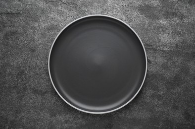 Photo of New dark plate on grey table, top view