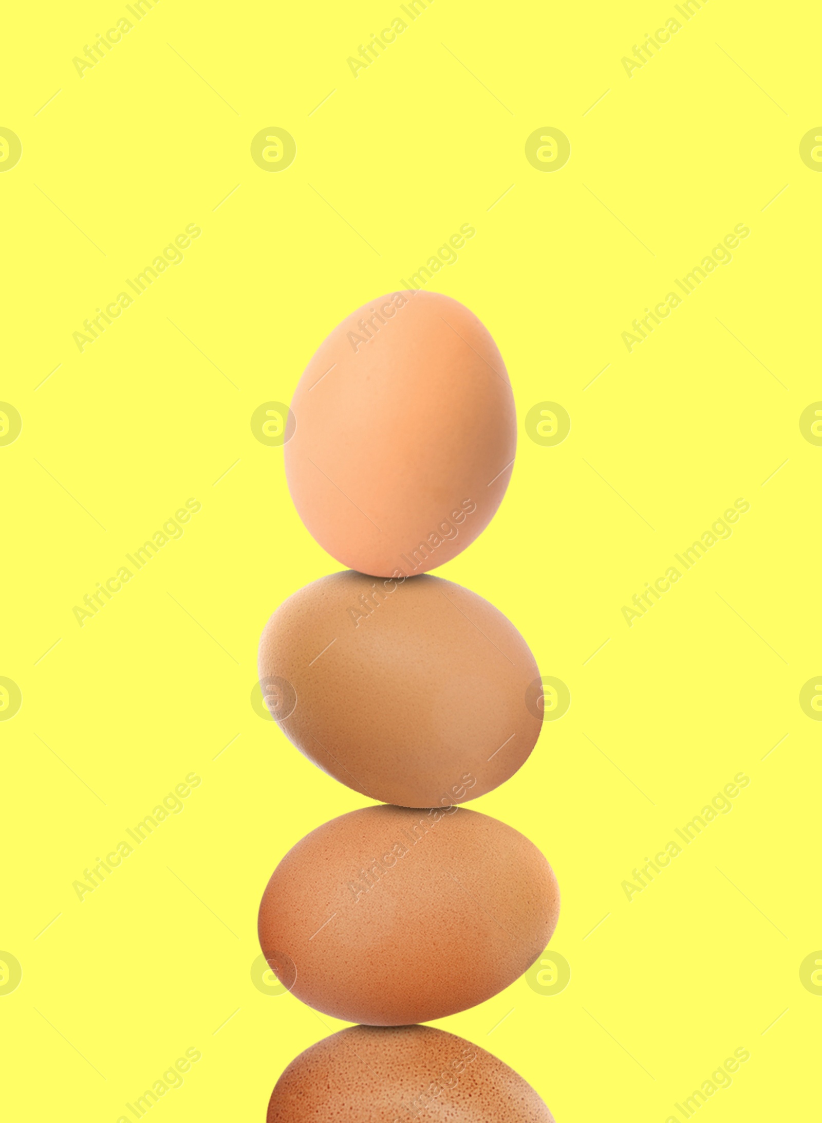 Image of Stacked fresh chicken eggs against light yellow background