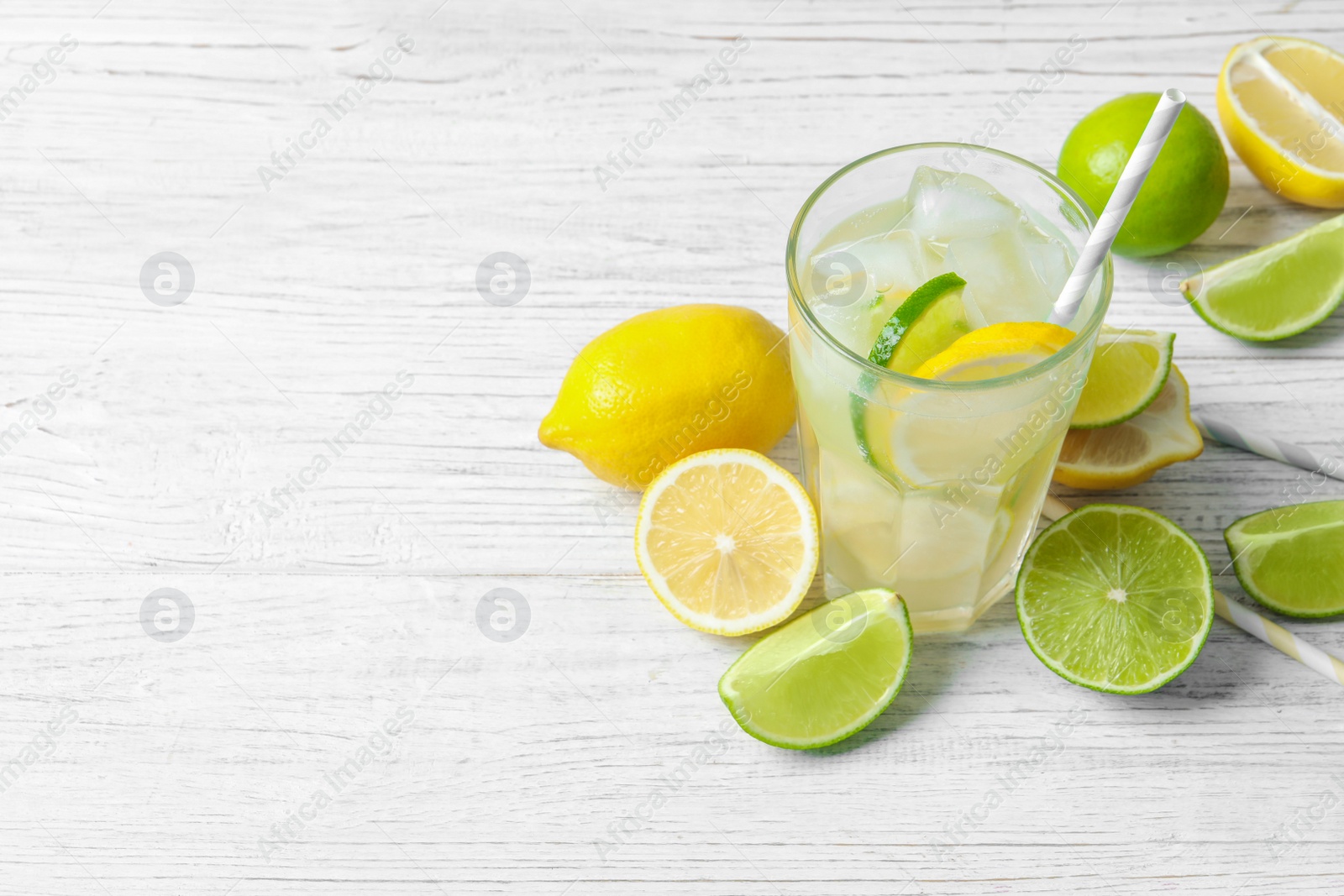 Photo of Glass of natural lemonade with citrus fruits on table