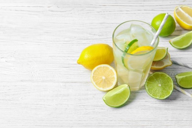 Glass of natural lemonade with citrus fruits on table