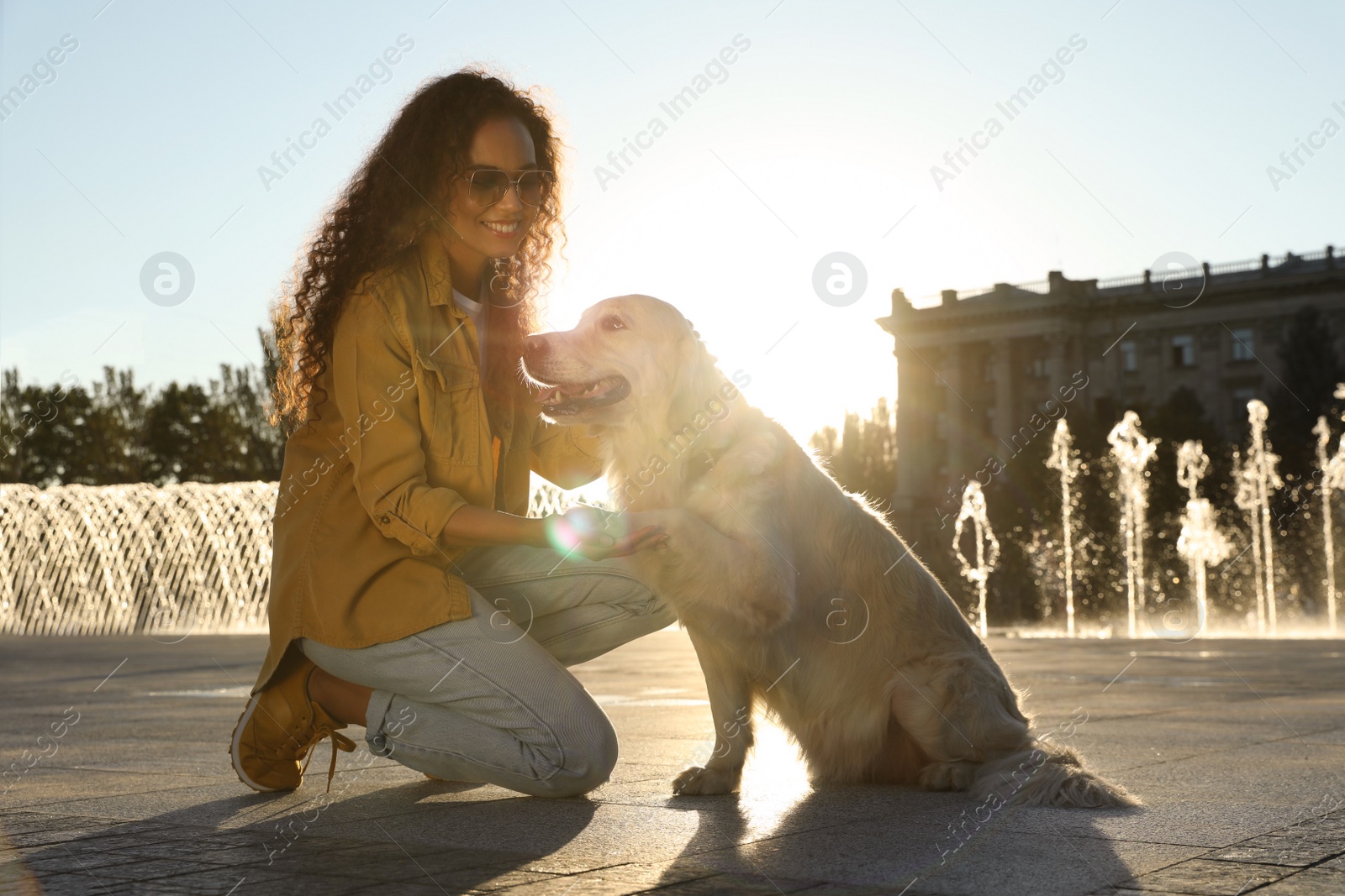 Photo of Young African-American woman and her Golden Retriever dog outdoors