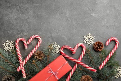 Photo of Flat lay composition with candy canes and Christmas decor on grey table. Space for text