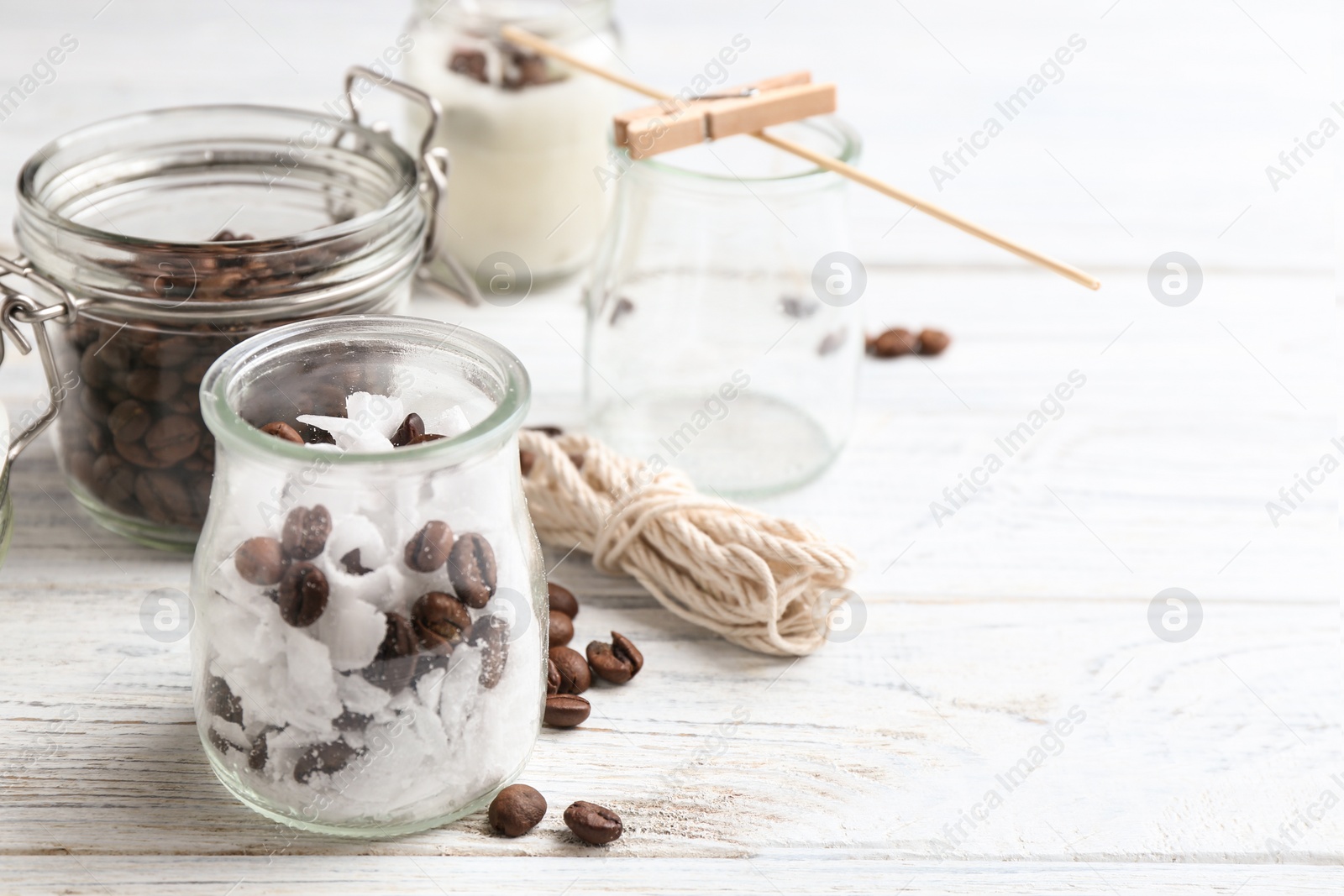 Photo of Glass jar, wax and coffee beans for making handmade candle on wooden table. Space for text