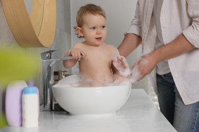 Photo of Father washing his little baby in sink at home