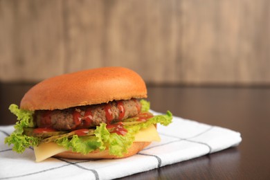 Photo of One tasty burger with patty, lettuce and cheese on wooden table, closeup. Space for text