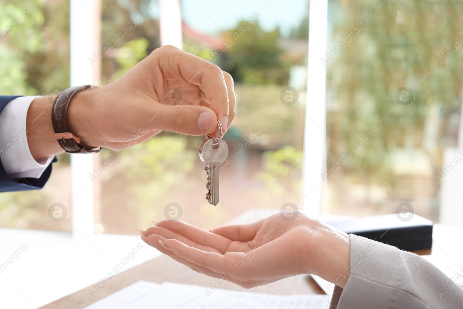 Photo of Real estate agent giving key to woman in office, closeup