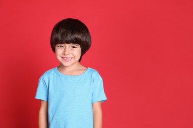 Portrait of cute little boy on red background, space for text