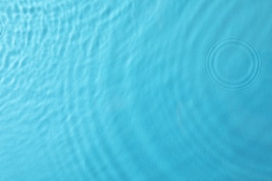 Photo of Clear water with rippled surface on light blue background, top view