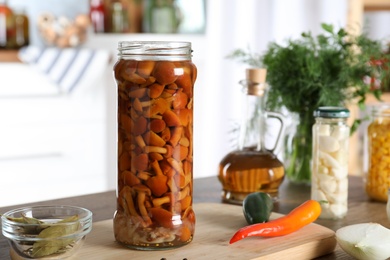 Jar with pickled mushrooms on wooden table indoors