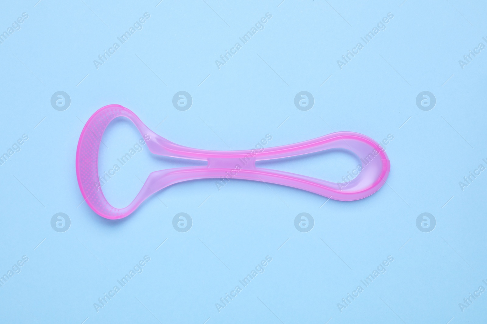 Photo of Pink tongue cleaner on light blue background, top view