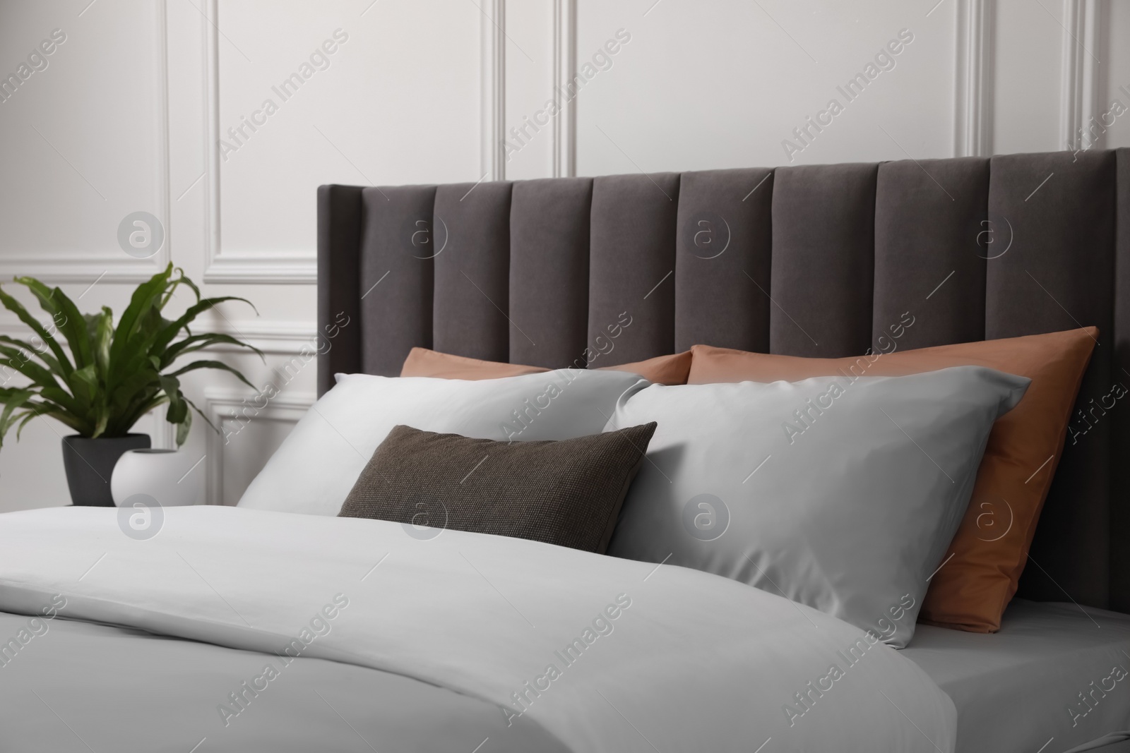 Photo of Comfortable bed with pillows and bedding in stylish room. Interior design