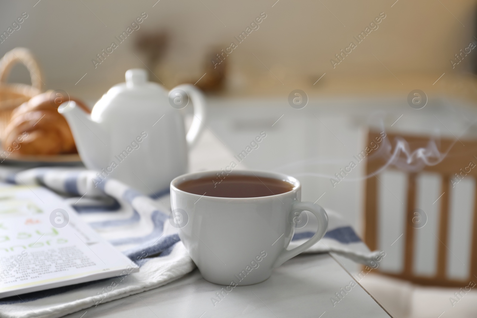 Photo of Cup of hot tea served for breakfast on table in kitchen