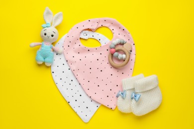 Photo of Flat lay composition with drool baby bibs and accessories on yellow background
