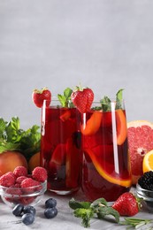 Photo of Delicious refreshing sangria with fresh fruits and berries on light grey table, space for text