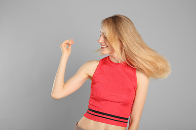 Photo of Portrait of beautiful young woman with blonde hair on grey background