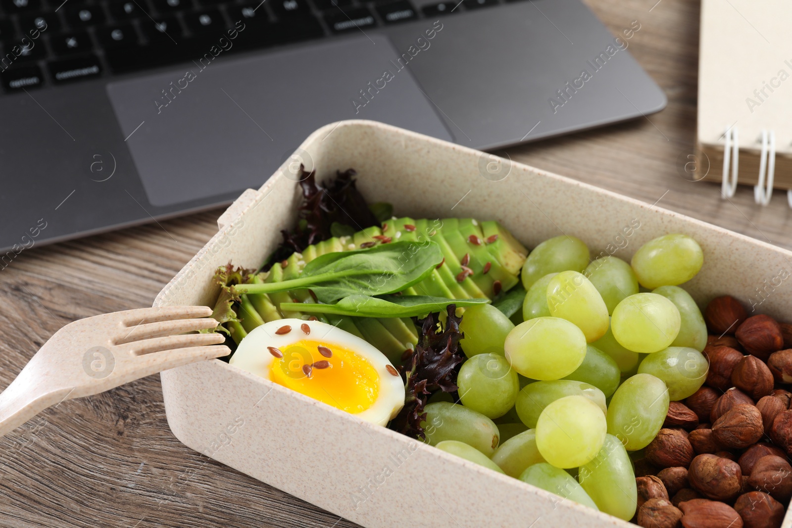 Photo of Healthy products high in vegetable fats near laptop on wooden table, closeup