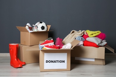 Photo of Carton boxes with donations on floor near grey wall