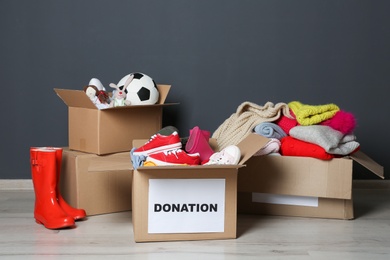 Carton boxes with donations on floor near grey wall