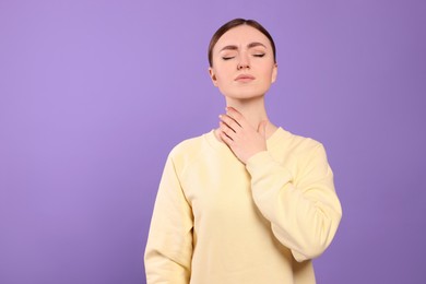 Young woman with sore throat on violet background. Space for text