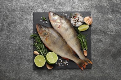 Photo of Fresh raw perches and ingredients on grey table, top view. River fish
