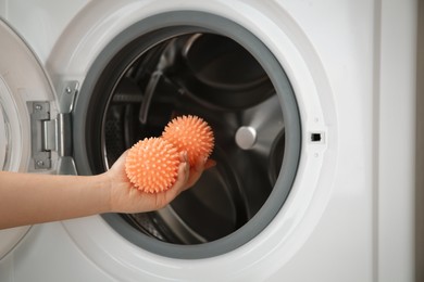 Woman putting dryer balls into washing machine, closeup