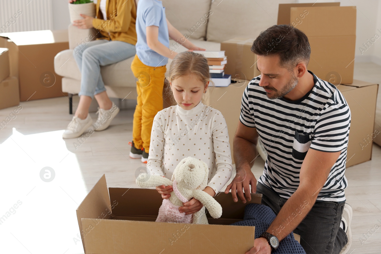 Photo of Family settling into home. Dad and daughter unpacking boxes in new apartment. Moving day