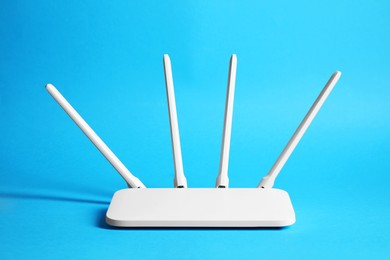 Photo of New white Wi-Fi router on blue background