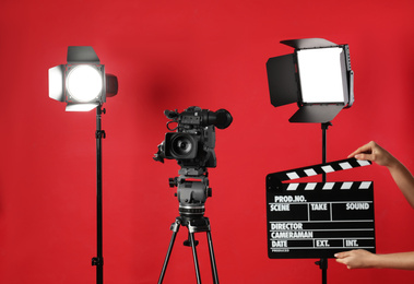 Photo of Woman with clapperboard near video camera in studio, closeup