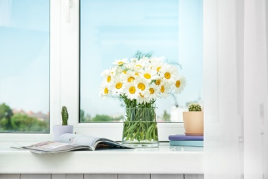 Photo of Vase with beautiful chamomile flowers on windowsill