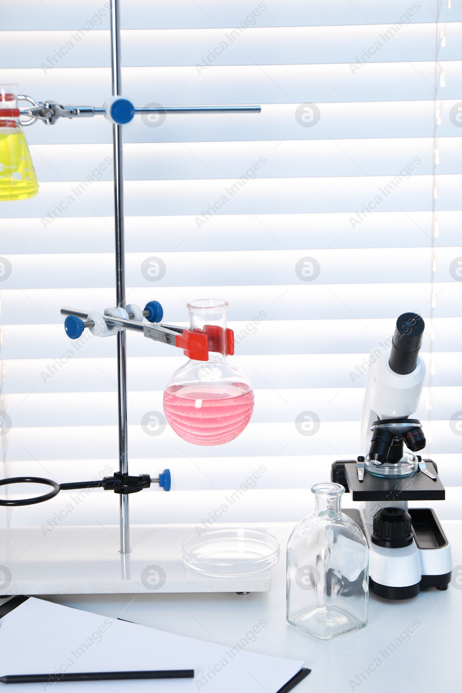 Photo of Laboratory analysis. Flasks with liquids and microscope on white table