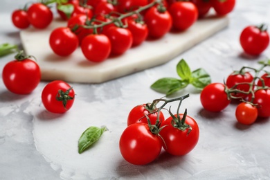 Photo of Fresh ripe cherry tomatoes and basil on light grey table